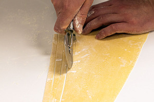 Pastateig mit dem Pizzaroller zu Tagliatelle schneiden