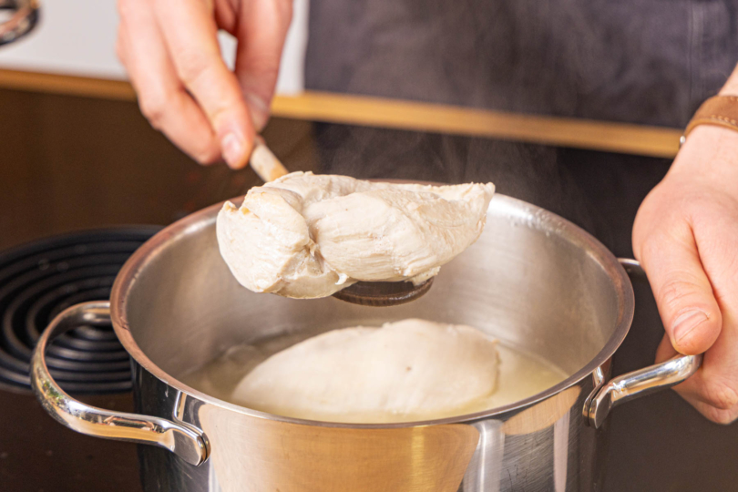 gekochtes Hähnchen aus Topf holen