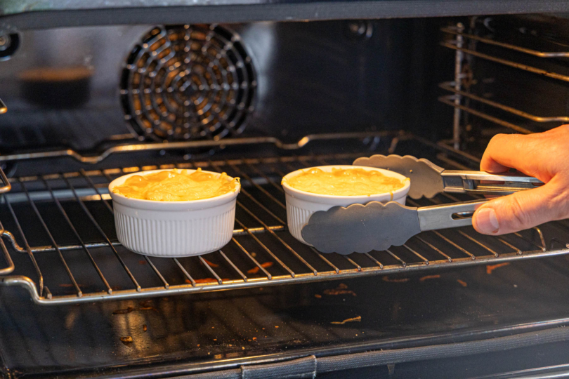überbackenes DDR-Würzfleisch mit Zange aus dem Ofen nehmen