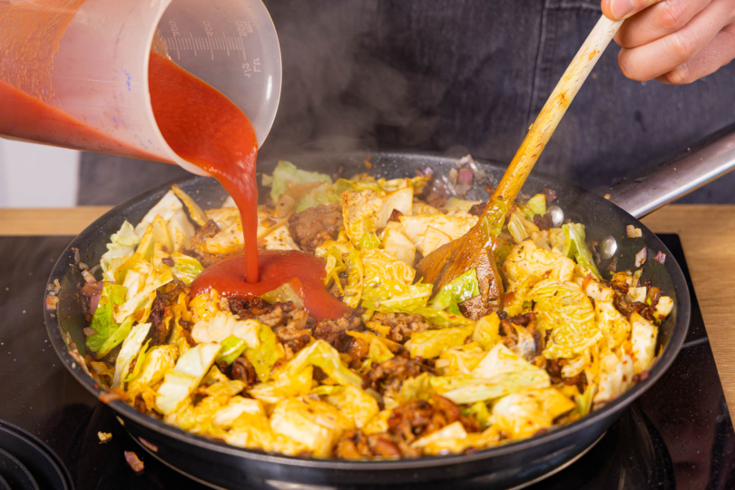 Brühe und passierte Tomaten mit in die Pfanne geben