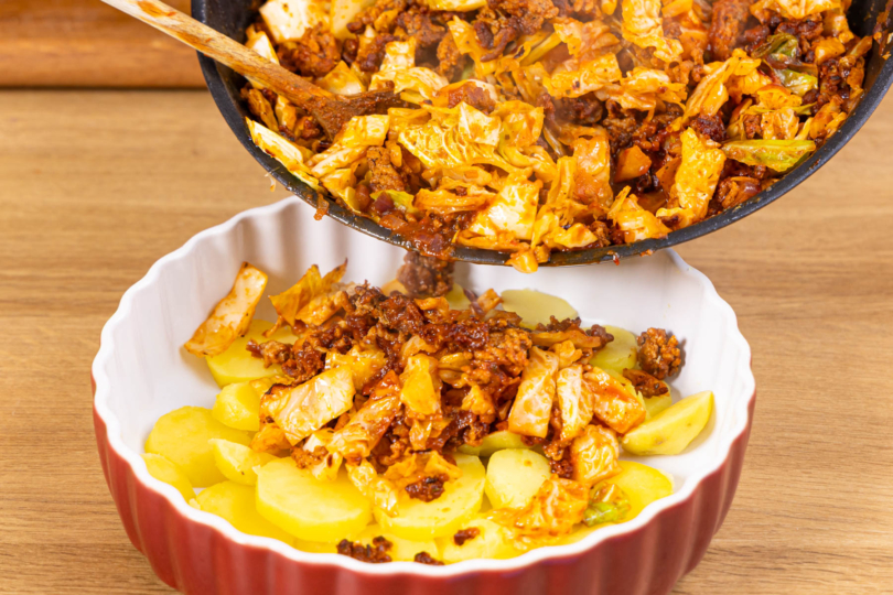 Wirsingauflauf mit Hackfleisch in der Auflaufform schichten