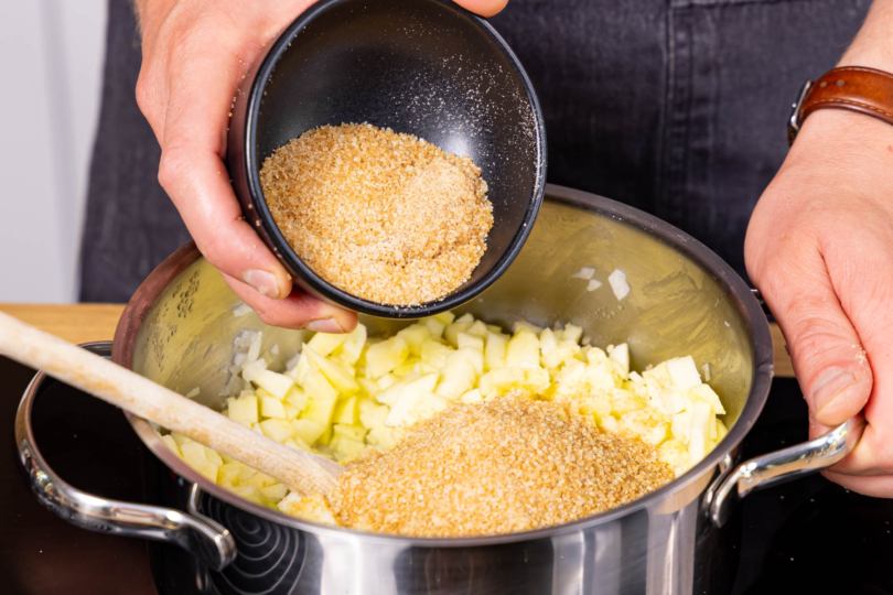 Zucker und Äpfel in den Topf geben