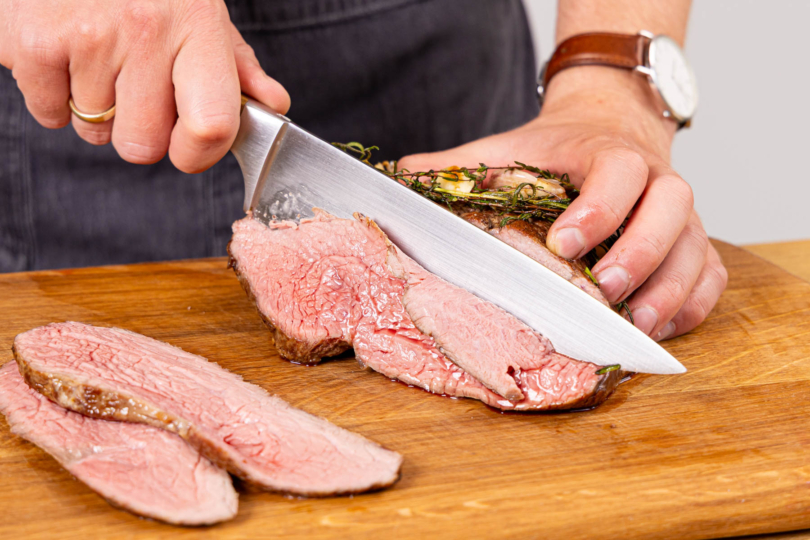 gegartes Roastbeef gegen die Faser in Tranchen schneiden