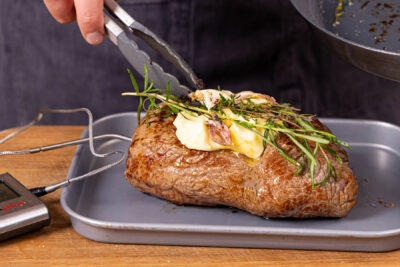 Butter und Kräuter auf das Fleisch legen und im Ofen garen