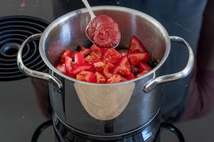 Tomatenmark in den Topf geben