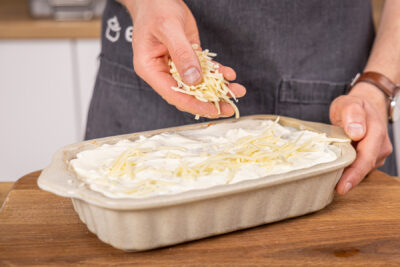 Käse über die Kohlrabilasagne streuen