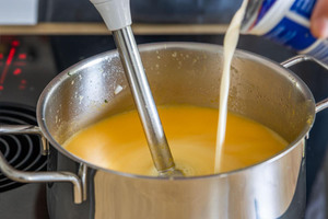 Sahne zur Kürbissuppe geben