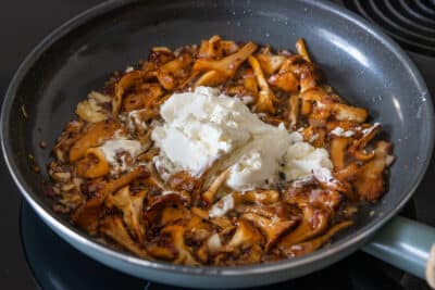 Frischkäse zu gebratenen Pfifferlingen geben