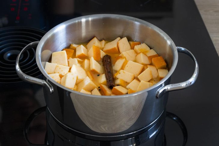 Kürbisstücke mit Orangensaft, Zimt und Vanillemark in einen Topf geben