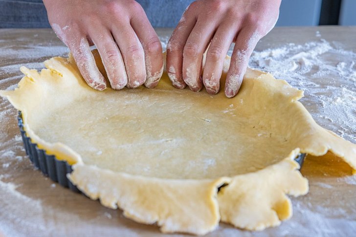 Boden der Tarteform mit Teig auskleiden