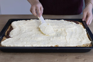 Creme auf dem Schneewittchenkuchen verteilen