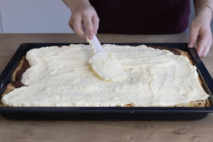 Creme auf dem Schneewittchenkuchen verteilen