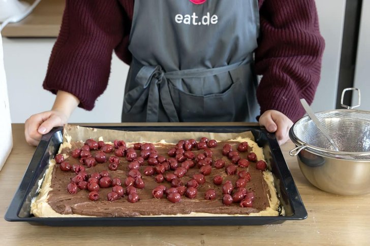 Kirschen auf den Teig des Schneewittchenkuchens vom Blech geben