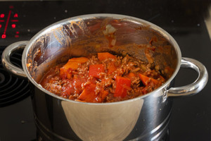 Kürbis und Tomaten in Topf geben