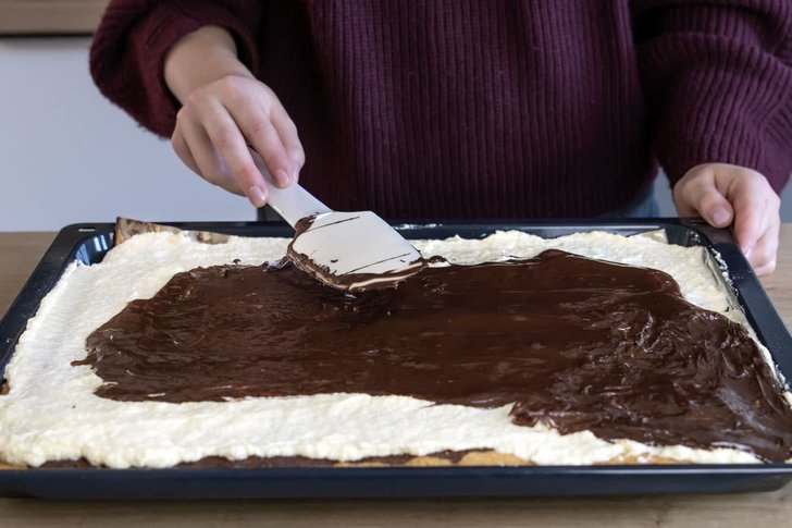 Kuvertüre auf dem Schneewittchenkuchen vom Blech verteilen