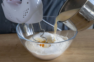 Milch in Mehl hineingießen