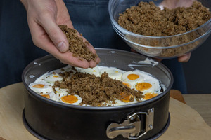 Brot über die Eierschicht der Brottorte streuen