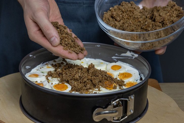Brot über die Eierschicht der Brottorte streuen