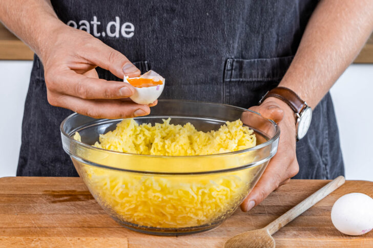 Ei und Eigelb in zerstampfte Kartoffeln untermengen