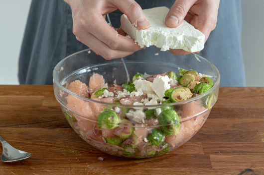 Feta über den Rosenkohl-Pomelo-Salat krümeln