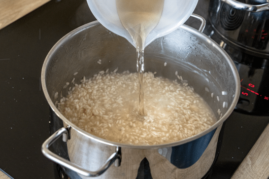 italienisches Zitronenrisotto mit Brühe ablöschen