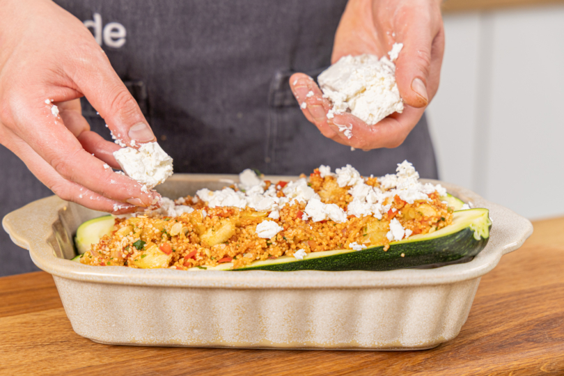 Feta über die Zucchini-Hälften bröseln