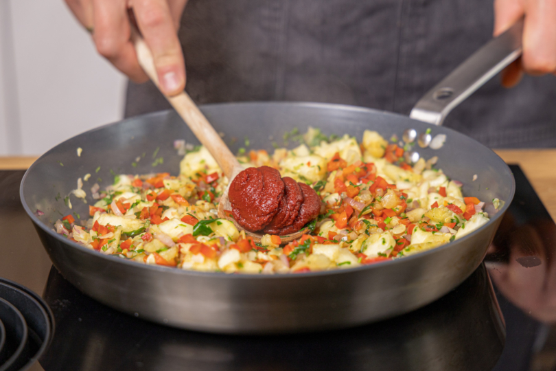 Tomatenmark in die Pfanne geben