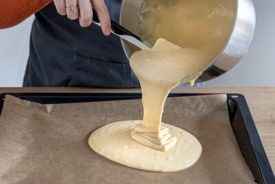 Kuchenteig auf dem Blech verteilen