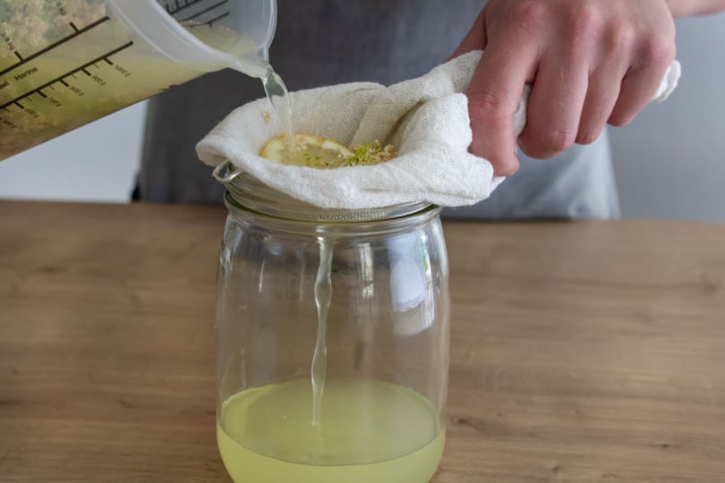 Holunder, Wasser und Zitrone durch Tuch gießen