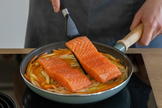 Lachsfilets auf Gemüsebett legen