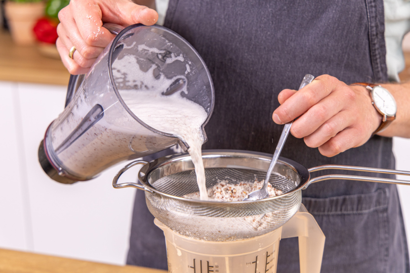 Mandelmilch durch ein Sieb streichen