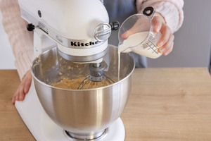 Milch zum Teig für Omas saftigen Nusskuchen geben