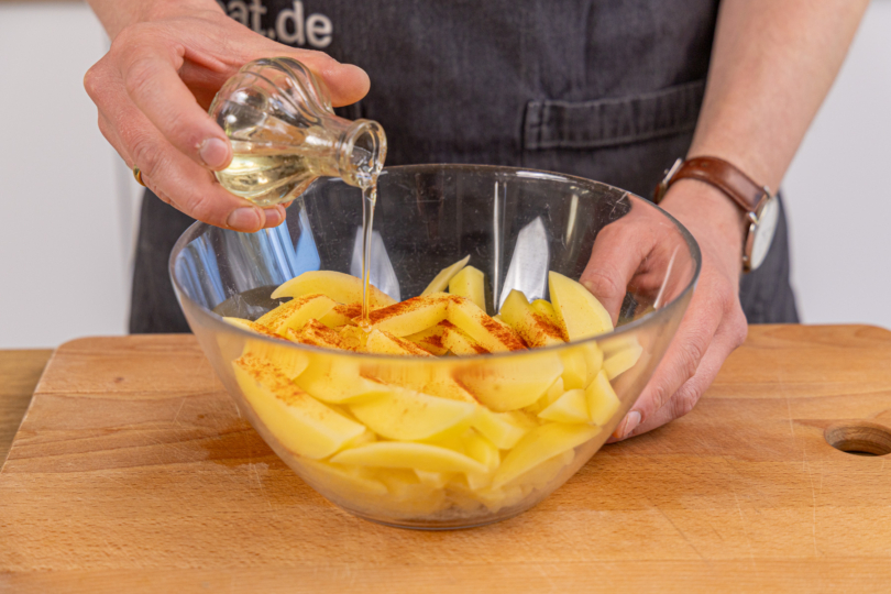 Pommes mit Öl und Paprikapulver würzen