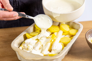 Auflaufsoße über Kartoffeln geben