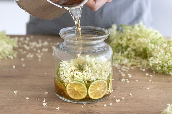Apfelsaft zu Holunderblüten gießen
