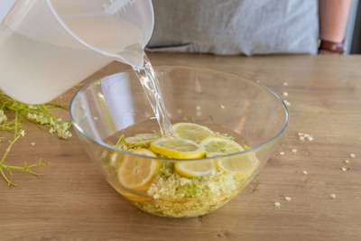 Holunderblüten und Zitrone mit Wasser übergießen