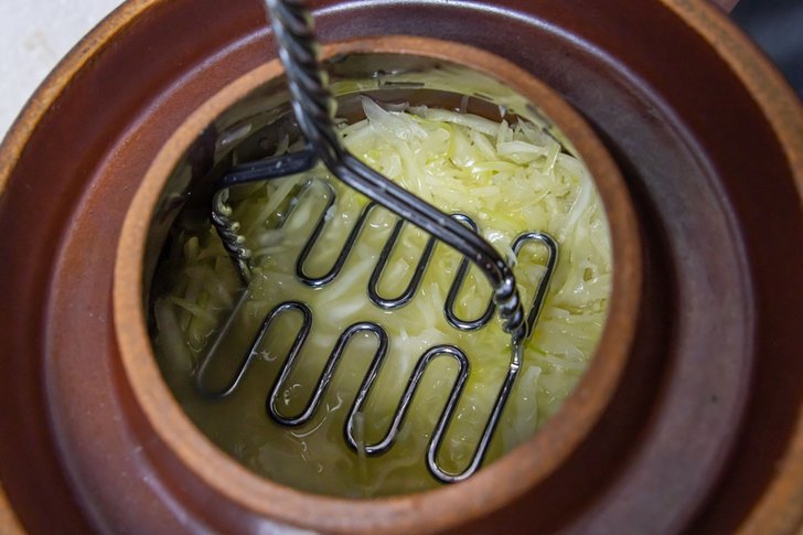 Sauerkraut im Steintopf stampfen