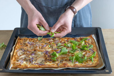 Felldsalat auf dem Flammkuchen verteilen