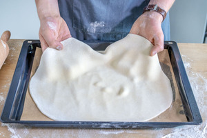 Flammkuchenteig auf ein Backblech legen
