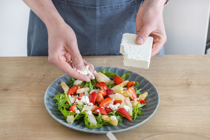 Feta über den Spargelsalat mit Erdbeeren bröseln
