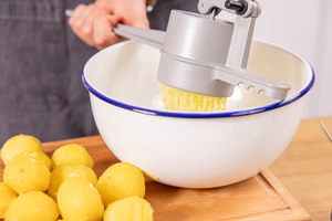 Kartoffeln durch die Kartoffelpresse drücken