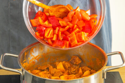 Paprika und Tomaten zum Gulasch geben