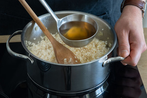Gemüsebrühe zum Risotto geben