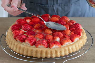 Tortenguss auf dem Erdbeerkuchen verteilen
