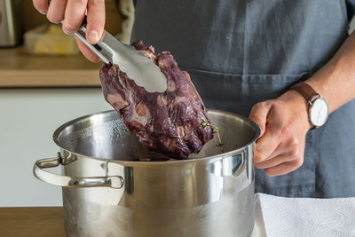 Eingelegte Wildschweinkeule aus Topf nehmen
