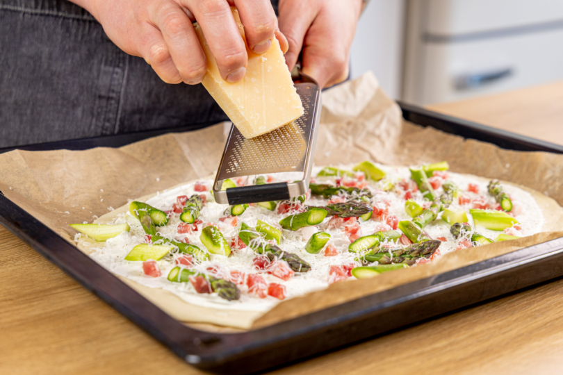 Käse auf den Flammkuchen reiben