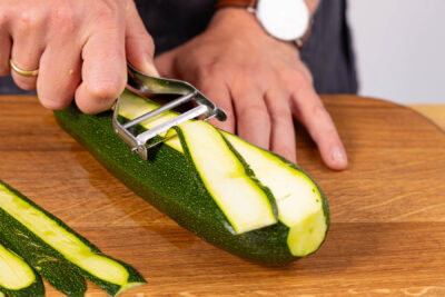 Zucchini mit einem Sparschäler in Streifen schneiden