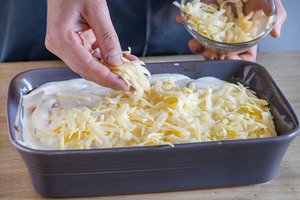 Geriebenen Käse auf Kürbislasagne verteilen
