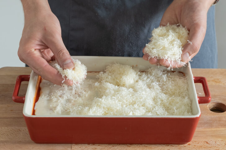 Parmesan auf den Cannelloni mit Spinat und Ricotta verteilen