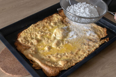 Puderzucker auf dem Huckelkuchen verteilen
